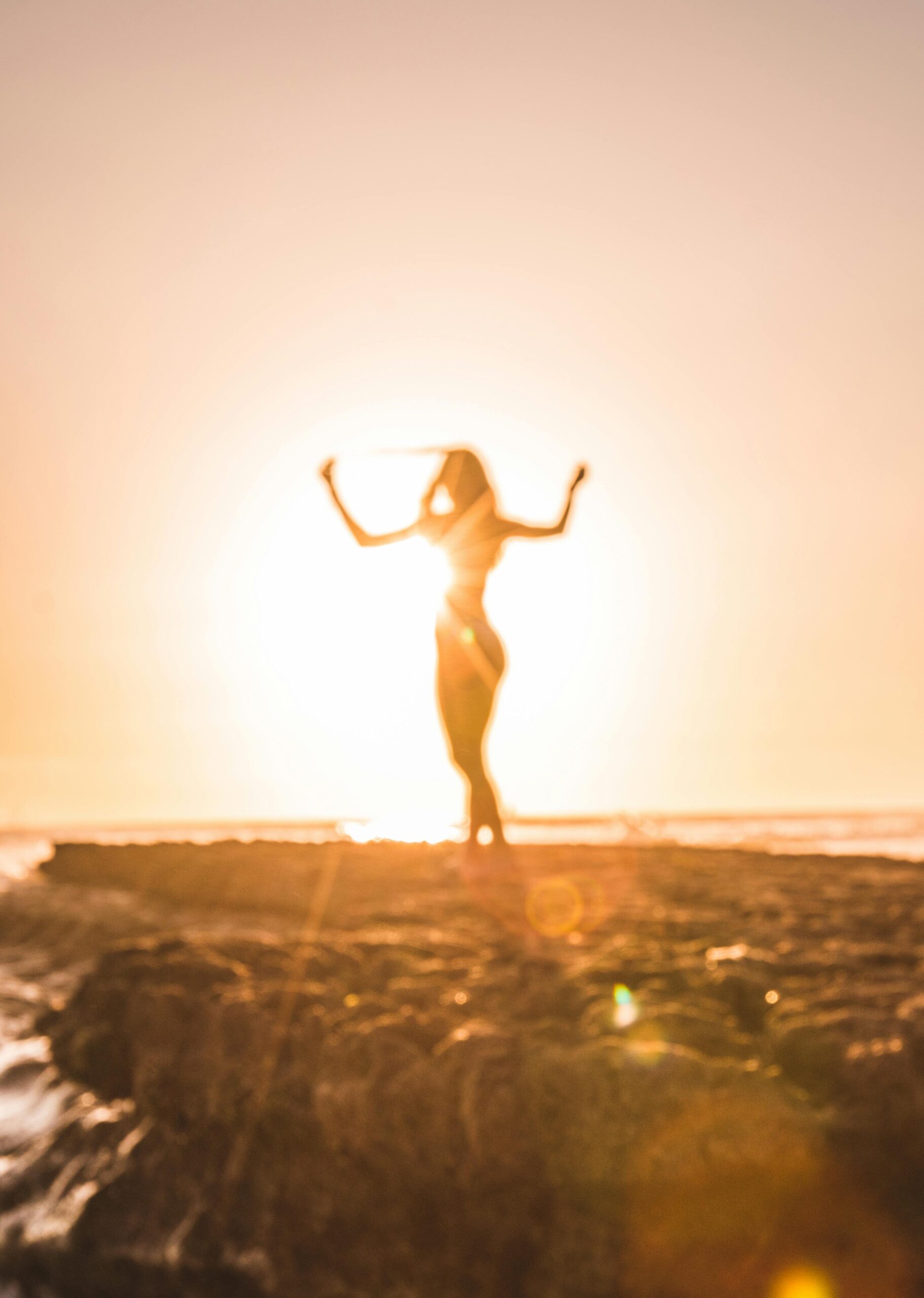A woman celebrates at sunset on a beach in San Diego, creating a stunning silhouette.